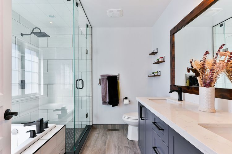 A modern bathroom with a glass shower, a toilet and a double vanity with black mixer taps