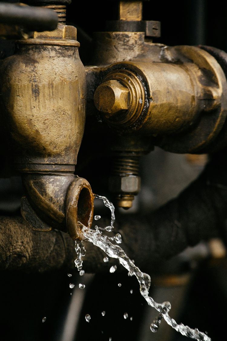 Water running from the outlet of an old brass valve