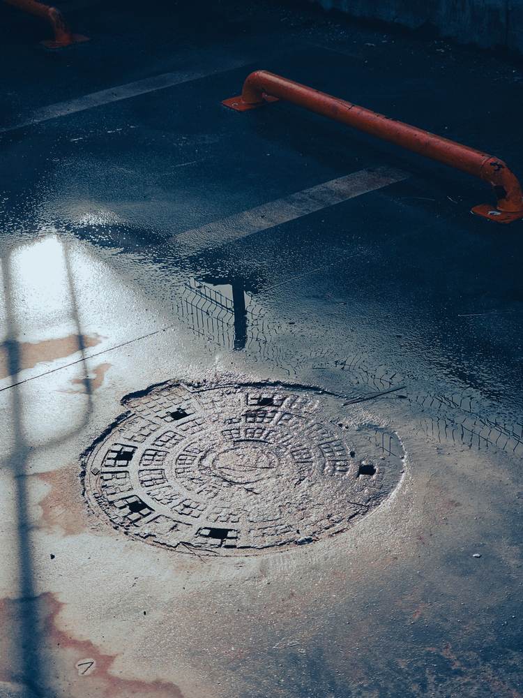 A round manhole cover on a wet yard surface