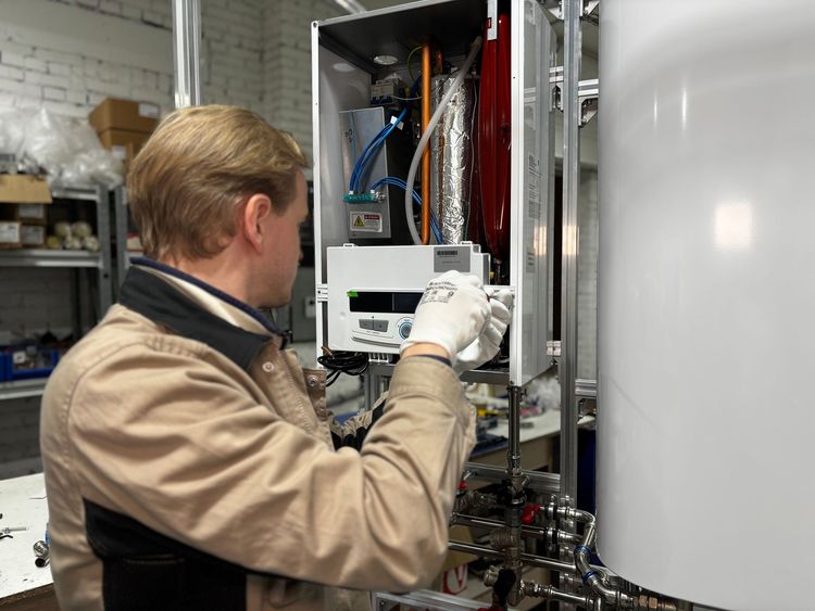 Technician in work gloves working on an open wall-mounted water heater
