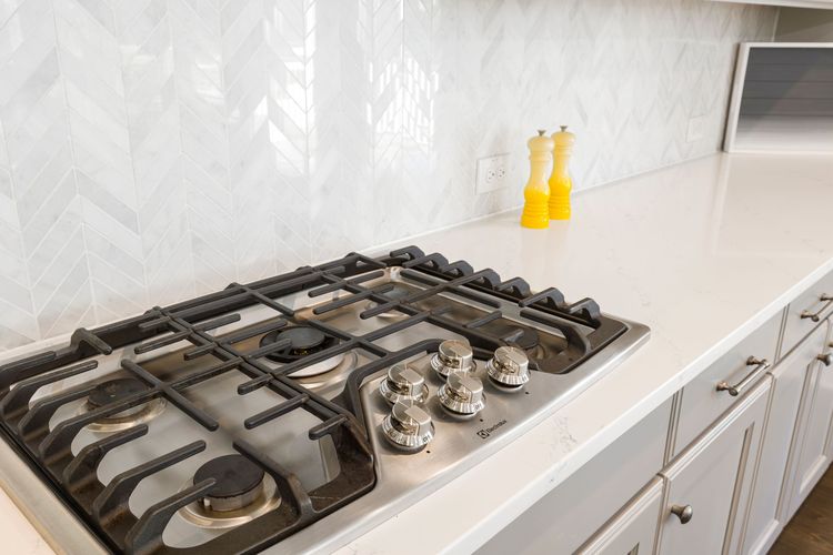 Five-burner gas hob set into a white kitchen counter