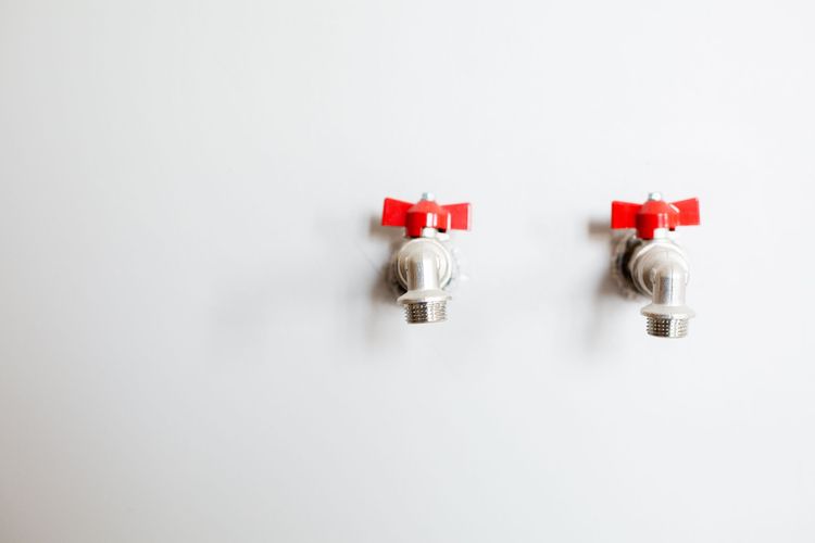 Two angle valves with red handles on a white wall