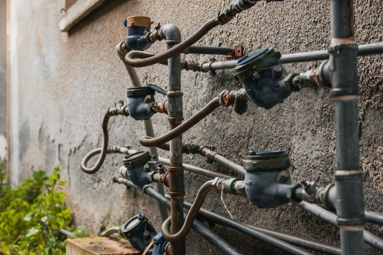 A row of water meters and pipework on an outside wall