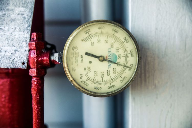 A round water pressure gauge, marked in psi and kPa, fitted to a red pipe