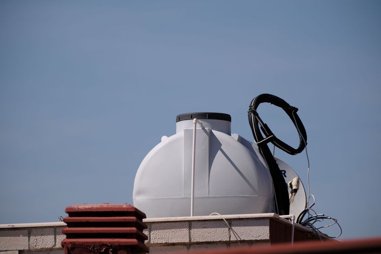 Plastic water storage tank on a roof against a blue sky